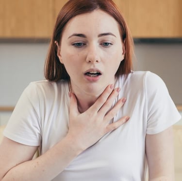 Woman sitting on couch, hands on chest. Get panic attack treatment in Vadodara from best psychiatrist near you