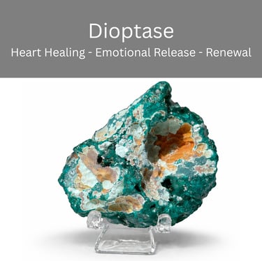 Emerald green Dioptase crystal cluster on a clear display stand for heart healing and emotional release.