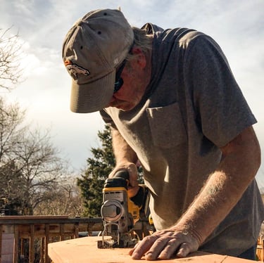Brewer Construction carpenter using an impact driver on a wooden deck structure in Evergreen.