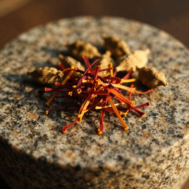Macro shot of saffron threads and cardamom pods resting on a textured granite grinding stone, warm golden hour light, shallow depth of field, 35mm film.