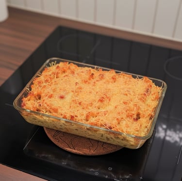 Gratin de macaronis dorés à l'emmental et lardons, nappe de sauce onctueuse au comté dans un plat