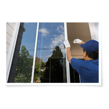 a man in a blue shirt and gloves fixing a sliding window