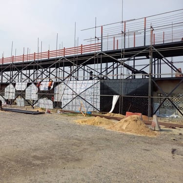SWEN Construction workers installing decorative facade panels on a steel scaffolding structure.