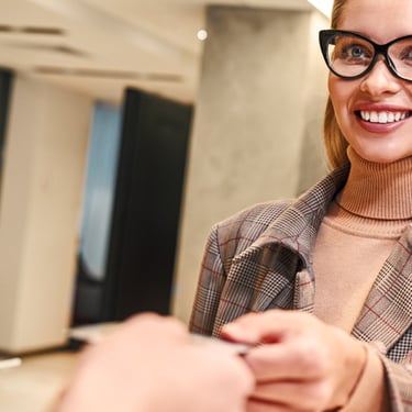 a woman in glasses and a suit jacket is smiling and holding a phone