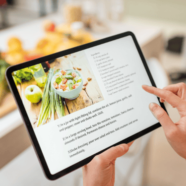 Person using a tablet to display a recipe. Ingredients are blurred out in the background
