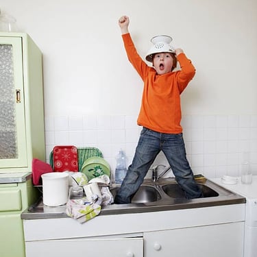 a young boy standing in a kitchen sink