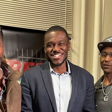 three men standing in a room with a guitar