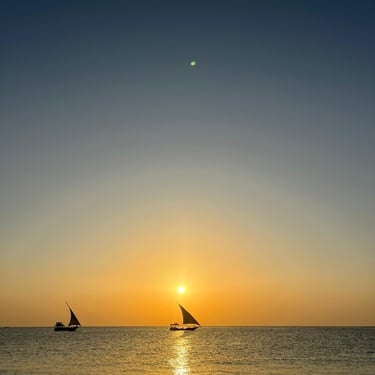 Tourists enjoying the stunning Zanzibar sunset on a traditional dhow cruise boat, surrounded by golden skies and calm waters