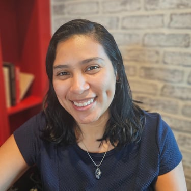Headshot image of Karen with a bookcase and brick wall background.
