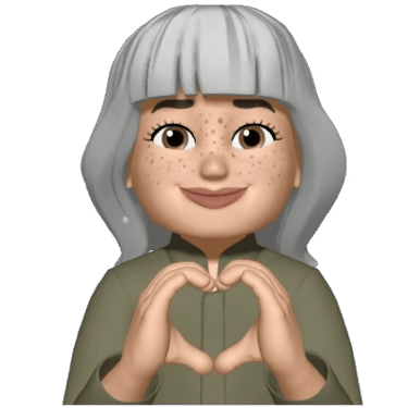 Female Memoji with grey hair and freckles making a heart shape with her hands.