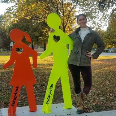 Mandy posing with a sculpture of two walkers