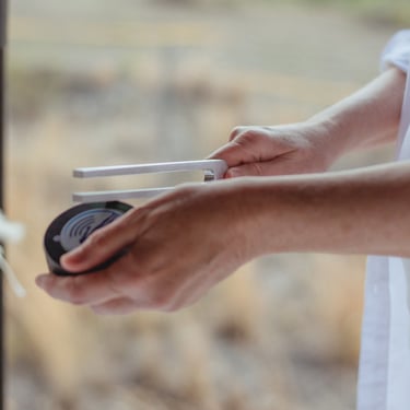 close up of Sheila Doerfler activating a tuning fork on the hockey puck in her left hand