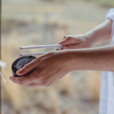 close up of Sheila Doerfler activating a tuning fork on the hockey puck in her left hand