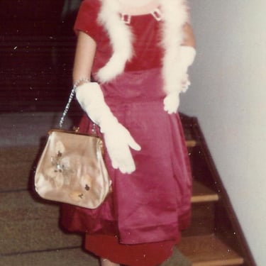 a young girl in a red dress and white fur stole