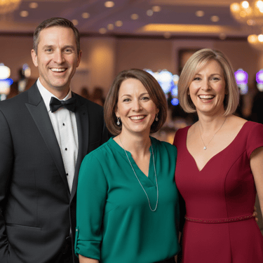 group of 3 people, 2 women wearing a red dress and a green dress and one man wearing a tuxedo