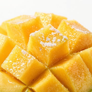 Macro shot of frozen mango cubes, vivid yellow-orange flesh, light frost dusting, crisp high-key commercial lighting