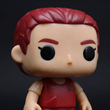 Detailed close-up of a premium vinyl collectible figure, high-contrast studio lighting, rich red accents, dark background.