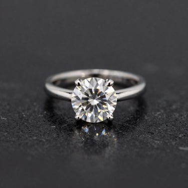 Macro studio shot of a brilliant-cut diamond ring on a black marble surface, shallow depth of field