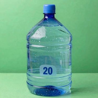 Pristine mineral water 20 liters blue gallon, clean and transparent, bright natural light, water droplets on the surface