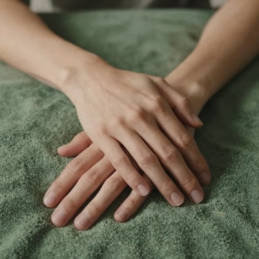 Close-up of two hands resting together on a soft green blanket, gentle indoor ambient light, warm and supportive.