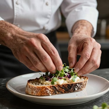 Close-up of a chef's hands carefully placing microgreens on a sourdough dish, low-contrast natural restaurant interior light.