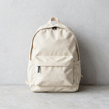 Structured everyday carry backpack made of durable canvas, flatlay on light concrete, soft daylight