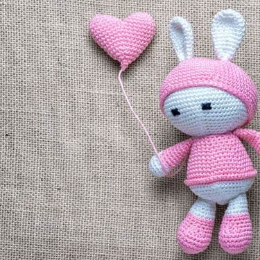Amigurumi de crochet hecho a mando de conejito con ropa en color rosa y globo de corazón
