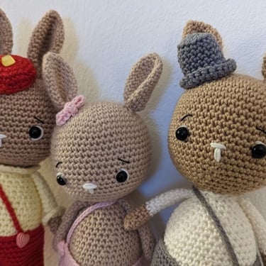 Conjunto de amigurumis hechos a mano de tres conejos cafés con ropa y sombrero