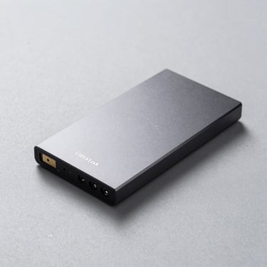 Ultra-slim portable solid-state drive on a textured light grey surface, professional product photography.