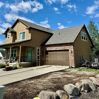 home with tan stucco and brown earthtones manufactured stone veneer prior to an exterior remodel
