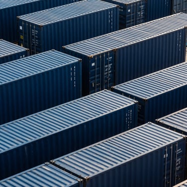 High-contrast technical studio photograph of a geometric grid of shipping containers at Mersin Port, high angle, sharp lines, deep navy and steel blue lighting, clean industrial composition.