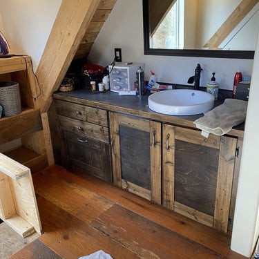 Rustic bathroom vanity with a vessel sink, dark wood cabinets, and a sloped wooden ceiling.