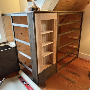 Custom wooden dresser storage unit under construction with tools on the floor.