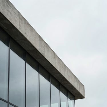 Abstract close-up of a modern concrete and glass structure, sharp lines, overcast sky, cool tones, architectural photography