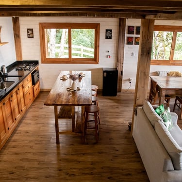 Cozinha completa da cabana Wolken Haus em Urubici com bancada grande Ilha com banquetas, sofá e mesa de jantar