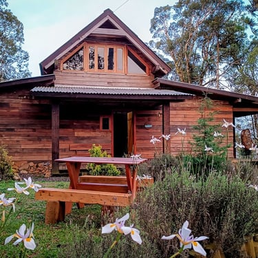 Jardim florido e frente da cabana de madeira em Urubici com mesa de jardim de muita natureza