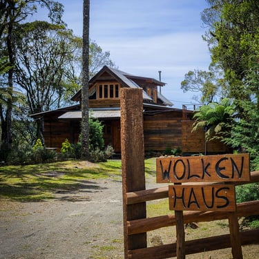 Acesso da Cabana rústica de madeira no Morro da Igreja com placa escrito Wolken Haus e céu azul