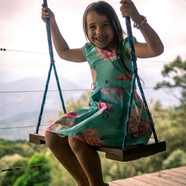 Menina sorrindo no balanço da varanda da cabana Wolken Haus Urubici com vista panoramica ao fundo