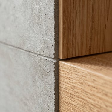 Extreme close-up macro shot of a perfect concrete pour transition meeting a warm oak wood panel, sharp architectural alignment, soft natural side lighting.