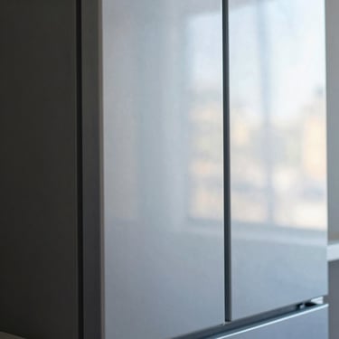 Close-up of a modern, sleek refrigerator door with a subtle reflection, industrial editorial photography, crisp daylight, cool blue and amber tones, sharp focus, technical detail, 35mm lens