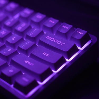 Moody close-up of a mechanical keyboard under purple neon backlighting, sharp focus.