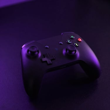 A high-contrast macro shot of a sleek black console controller resting on a dark reflective surface, purple highlights.