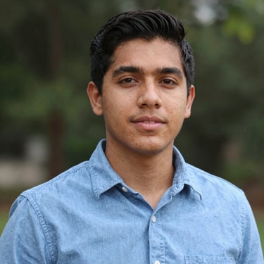 A smiling woman with curly hair enjoying a sunny outdoor cafe.
