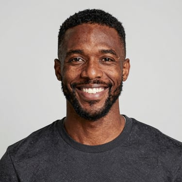 A smiling woman with curly hair enjoying a sunny outdoor cafe.