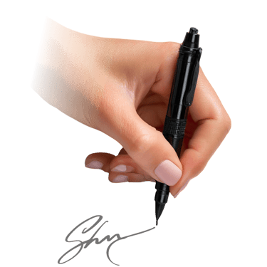 A woman's hand holding a professional black tactical pen writing a signature on a dark background.