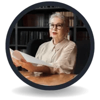 Professional senior woman with glasses reading a document in a library or office setting.