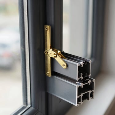 Close-up of a modern charcoal uPVC tilt and turn window profile, showing the dual-action brass hinge mechanism in open position.