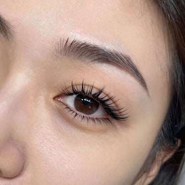 Elegant woman with long, voluminous eyelash extensions smiling softly