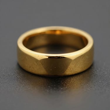 Macro product photography of a solid 22-karat gold ring, showing geometric detailing, deep shadows, warm gold reflections, shallow depth of field.