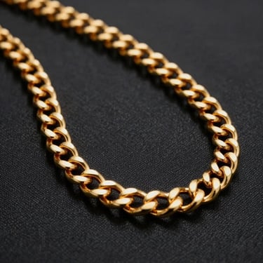 A heavy, hand-polished gold chain draped elegantly on a dark textured canvas, warm gold reflections, dramatic lighting.